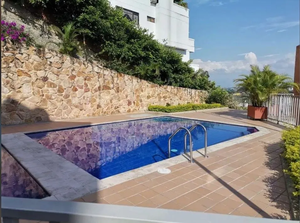 Piscina del condominio junto a un muro de piedra